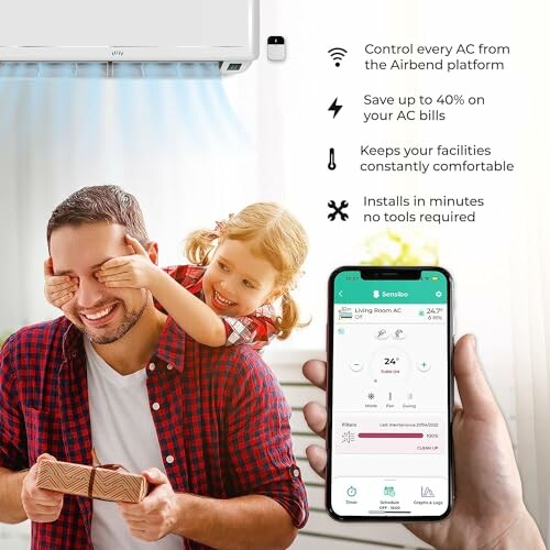 Man with child adjusting AC via smartphone app.