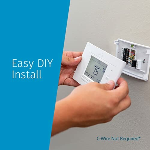 Person installing a smart thermostat on a wall.